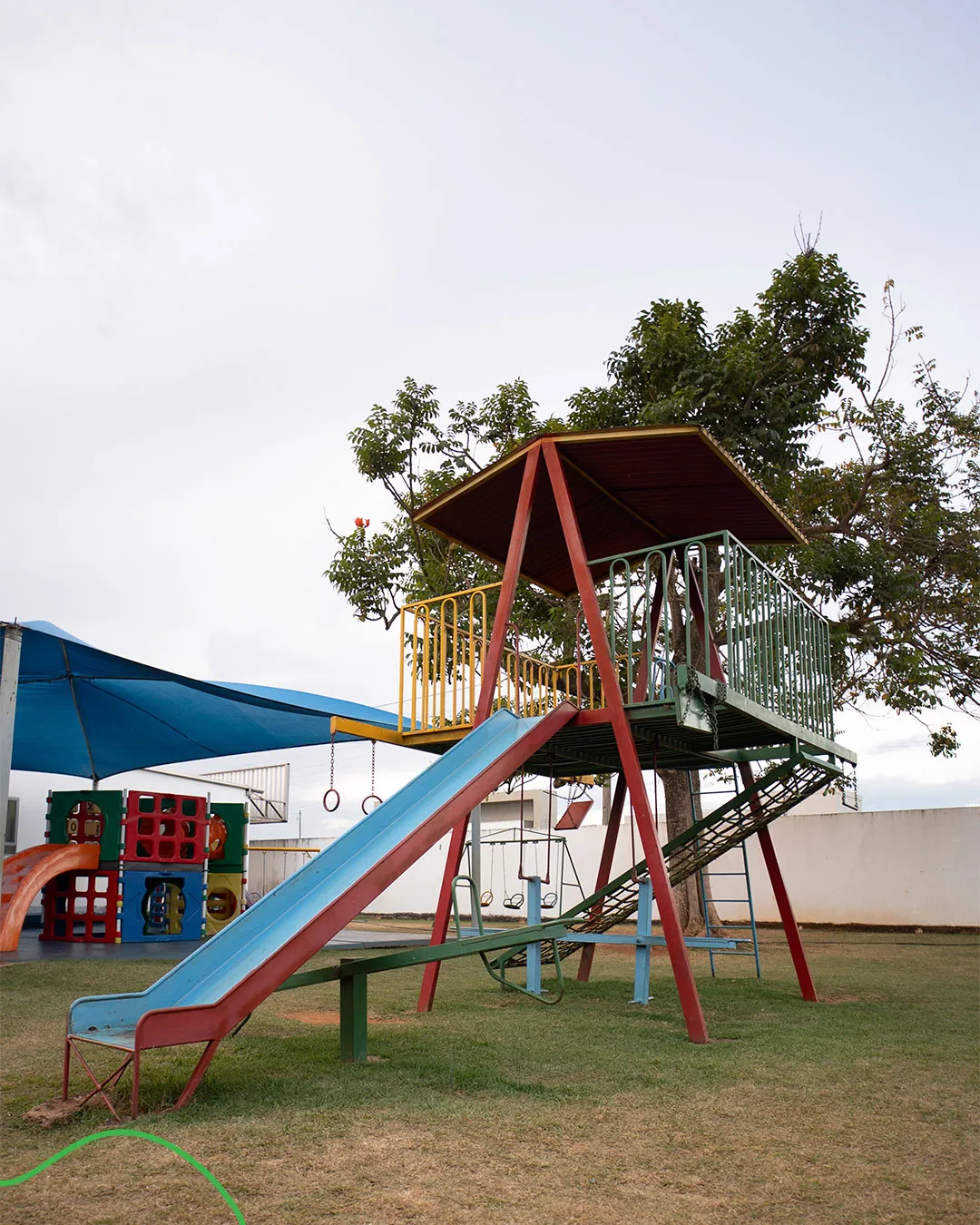 Parquinho da escola com escorregador e casinha na grama